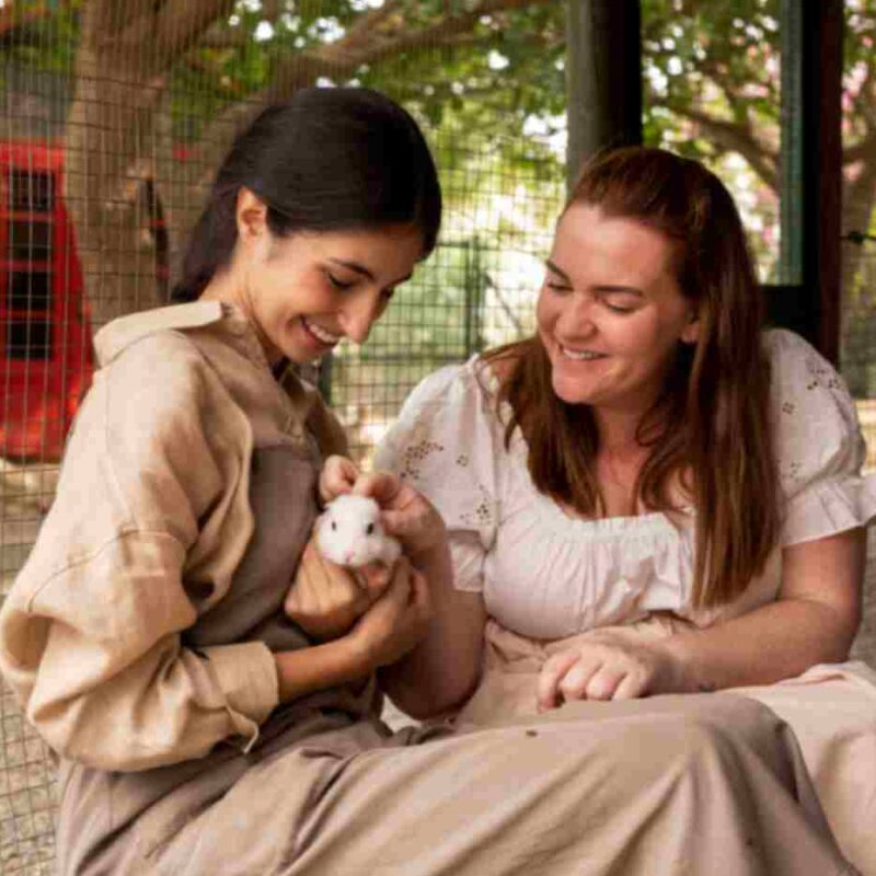 Two women gently holding a small rabbit, symbolizing the human-animal bond and the emotional connection between people and pets.