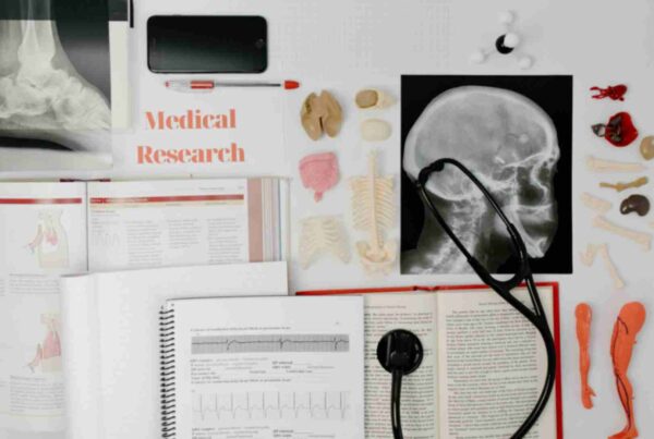 Medical research materials, including anatomy models, an X-ray image of a skull, medical textbooks, a stethoscope, and a phone, representing the study and practice of healthcare.