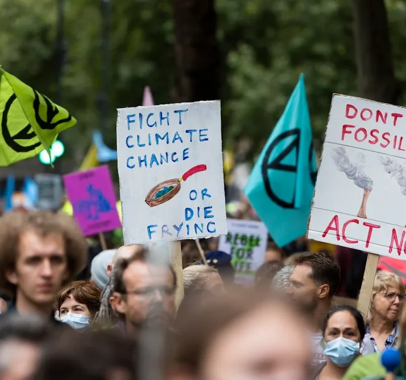 Climate activists protest urging action against climate change, with messages like 'Act Now' and 'Fight Climate Change.