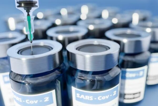 Close-up of SARS-CoV-2 vaccine vials with a syringe, representing advancements in medical research and production technologies.